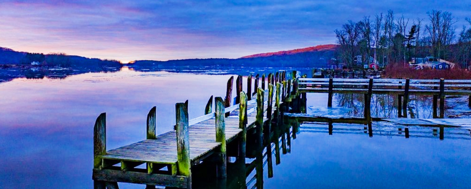 A serene dock at sunset, framed by a blue sky and winter surroundings.