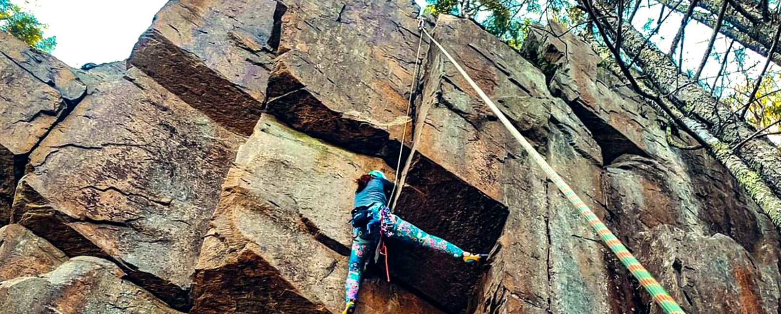 A climber ascending a rocky wall using ropes.