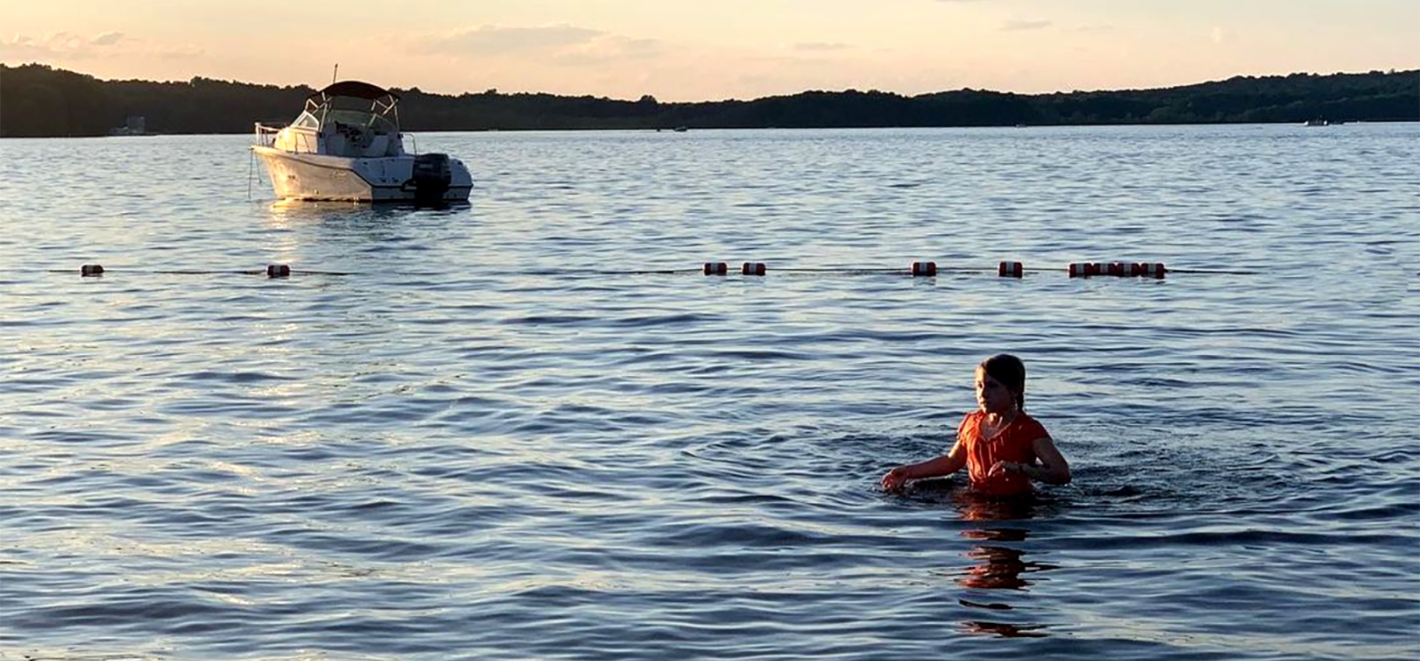 girl swimming in lake with boat in background (Instagram@saratedidee)