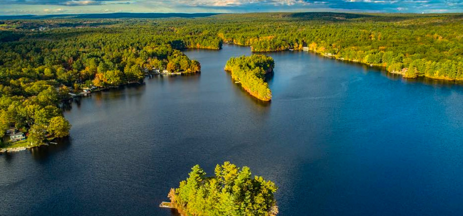 A serene lake nestled amidst lush greenery pictured from above.