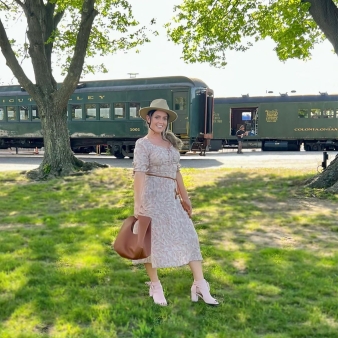 A woman posing in front of a train (Instagram@coralmagiera)