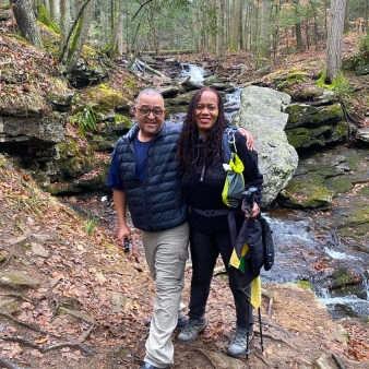 A couple hiking near a stream in the woods (Instagram@luuvnuv)