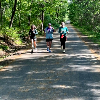 Three women running on a road in the woods