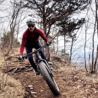 A man mountain biking through the woods (Instagram@mick.ferraro)