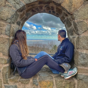 Couple on wall seat at top of Sleeping Giant State Park (Instagram@andiamoadventure)
