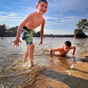 Two boys splashing and having fun in the water on a sunny day.
