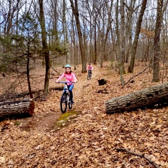 Two girls exploring a forest trail on their bikes.