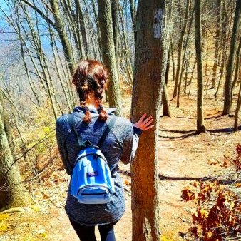 A woman with a backpack enjoying nature on a hiking trail.